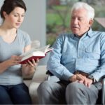 Caregiver reading to client in wheelchair